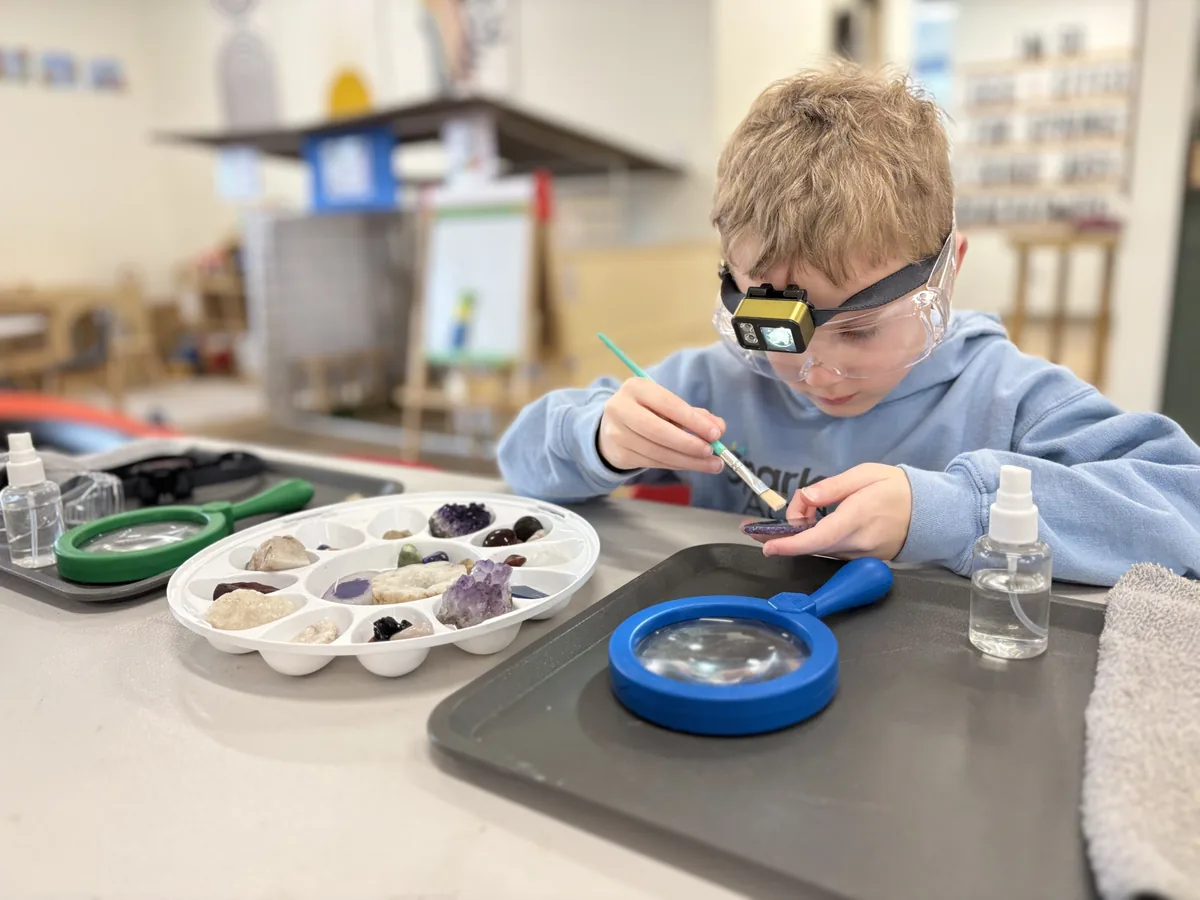 Student wearing safety goggles to examine minerals and rocks during a STEM class at Discovery Station
