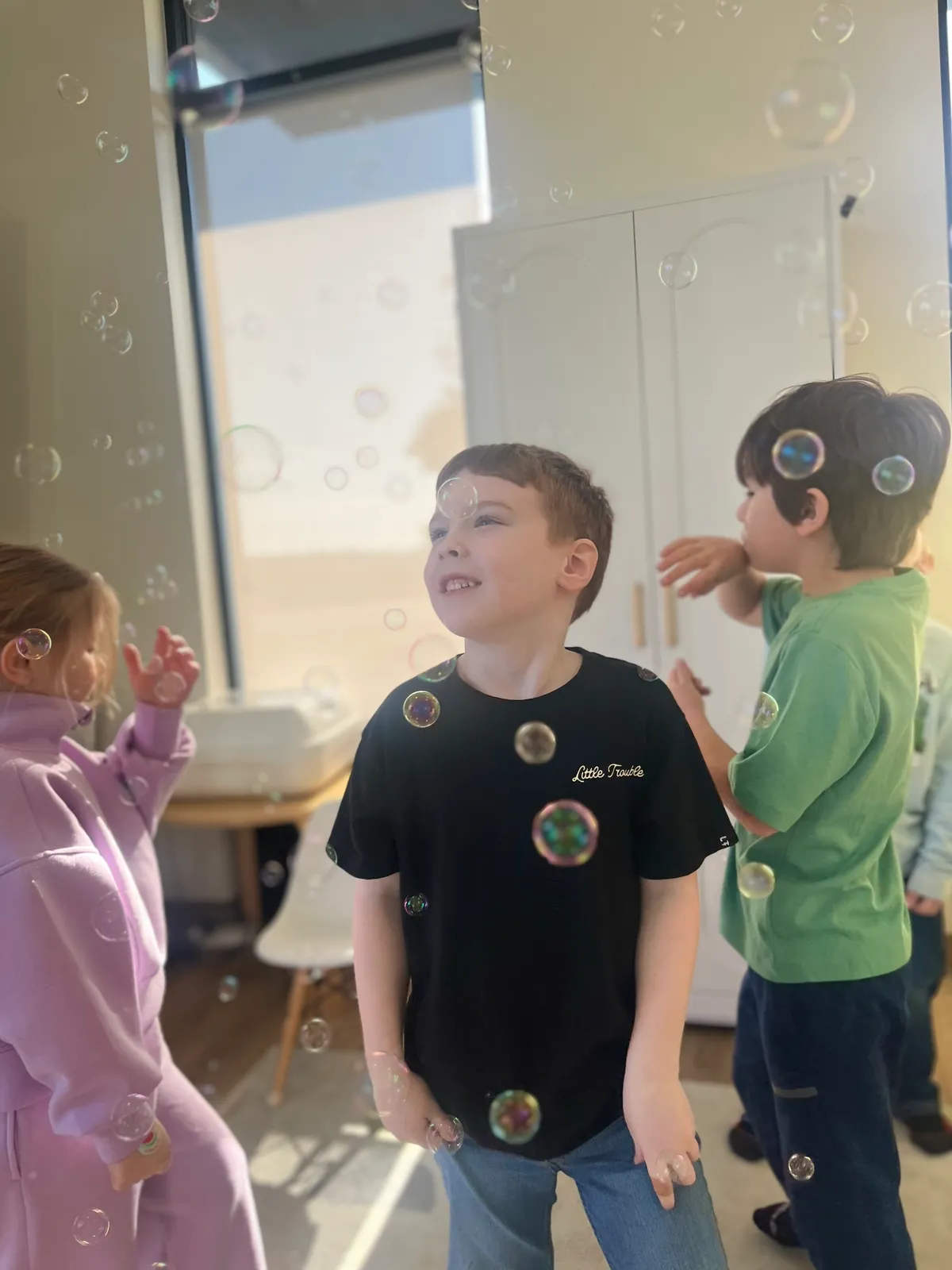 Child surrounded by floating bubbles during a summer activity at Spark Academy Camp Play