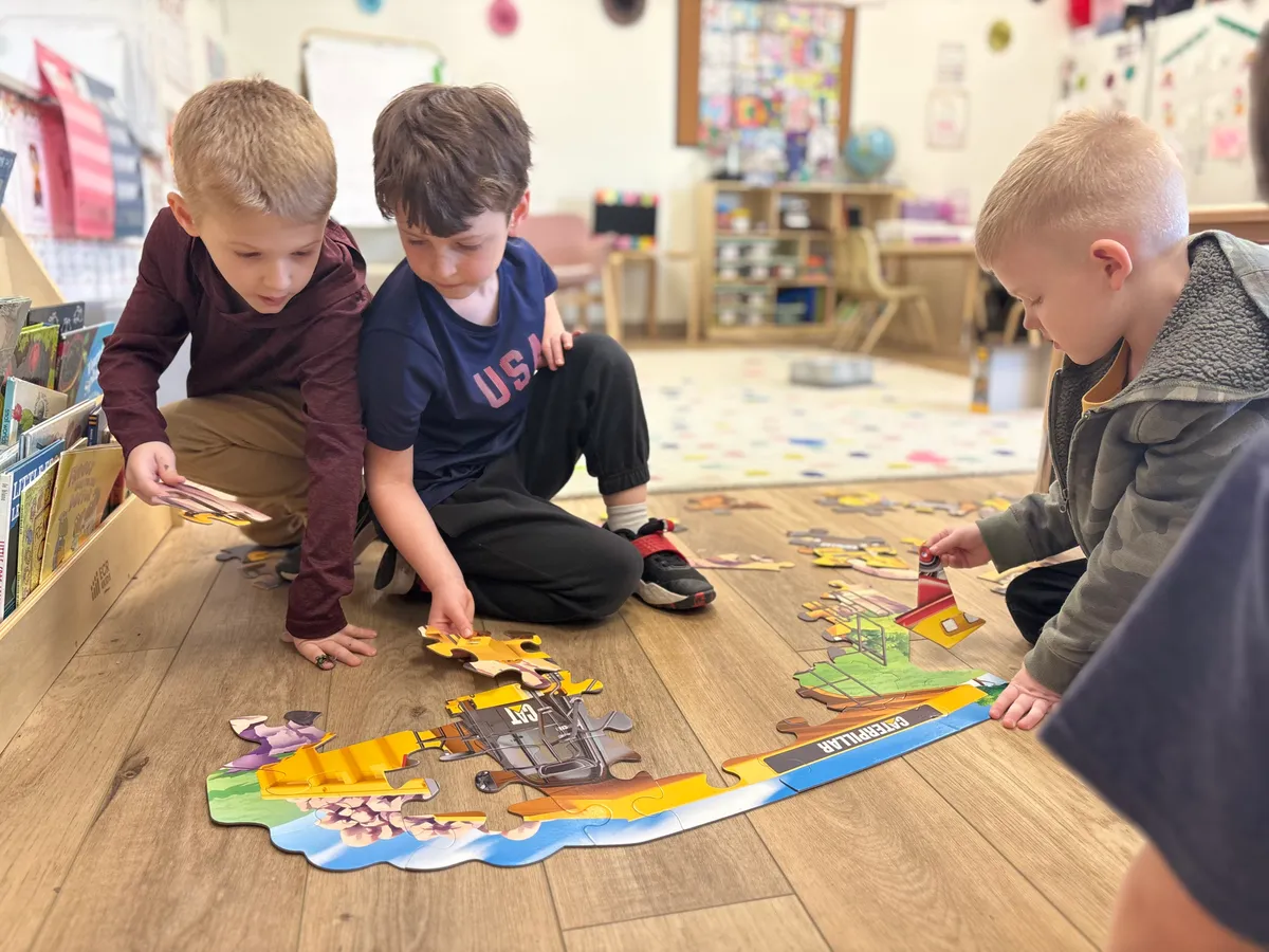 Preschoolers collaborating on a floor puzzle — purposeful play building problem-solving skills