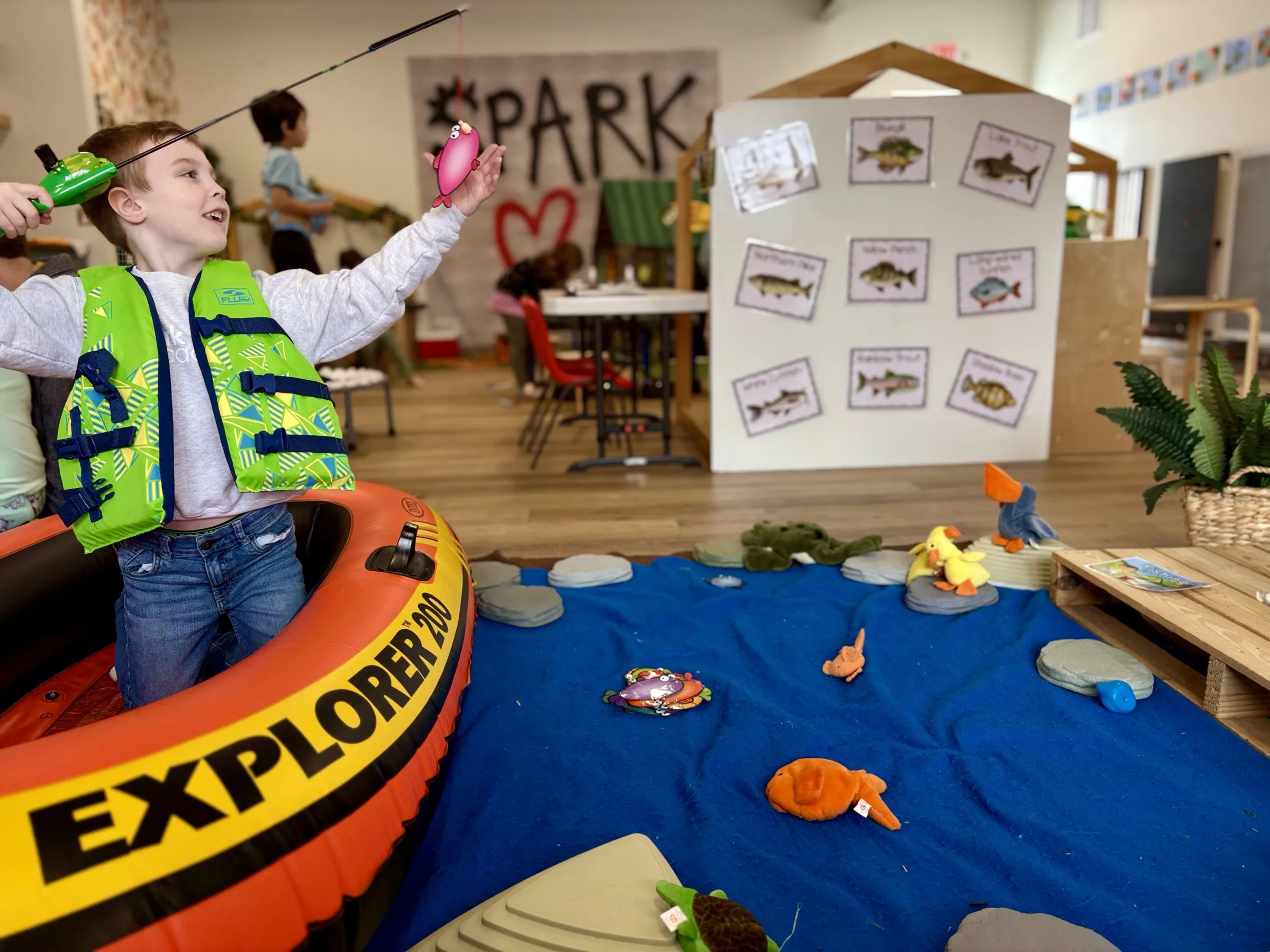 A child catching pretend fish in the Developmental Playroom at Spark Academy's Fresh 3's Fridays program
