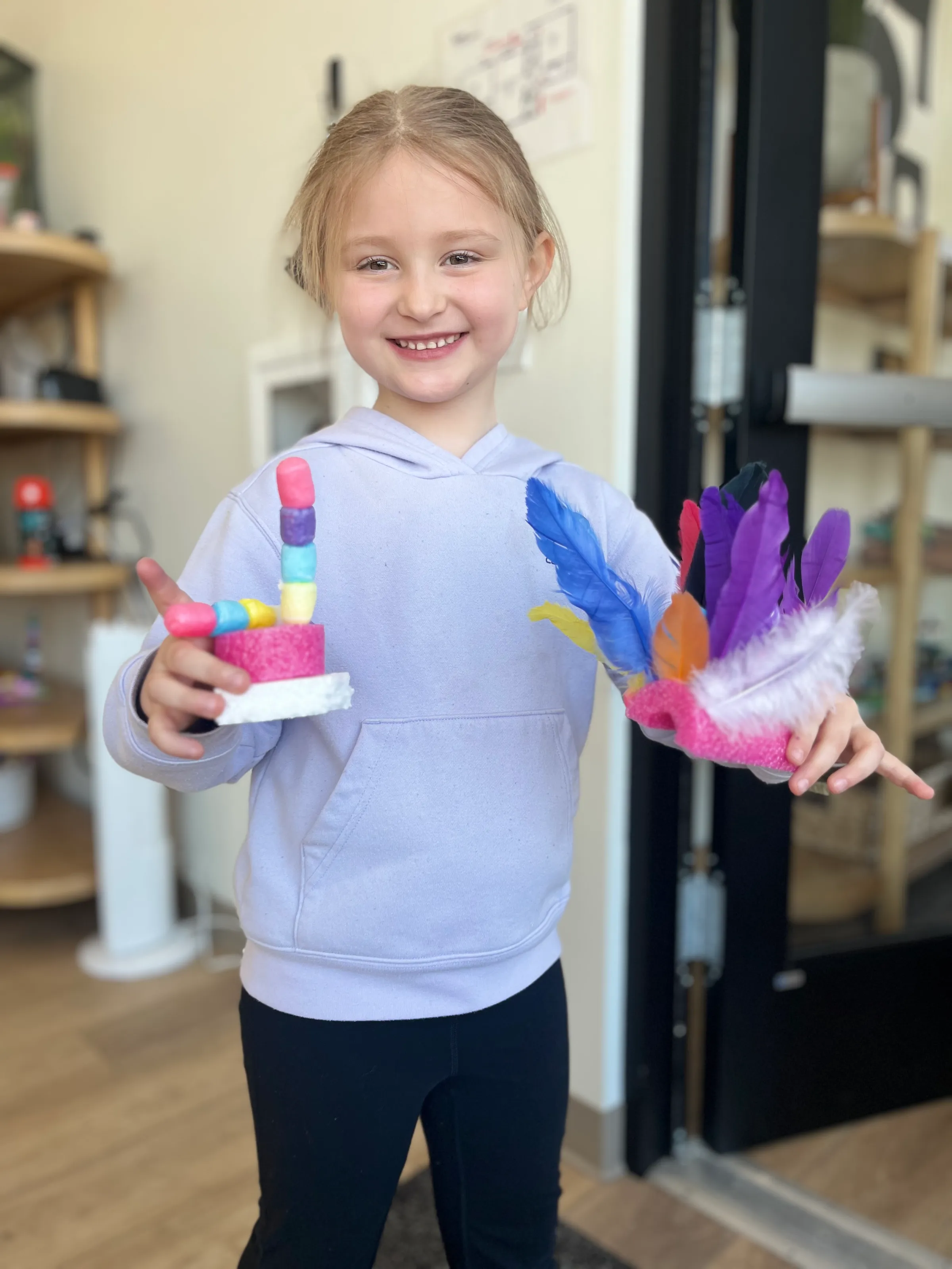 Discovery Station student proudly displaying handmade art creations at Spark Academy