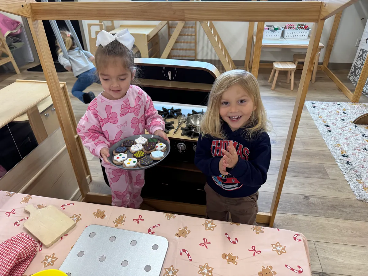 Two preschoolers serving cookies from the play kitchen during Fresh 3's Fridays at Spark Academy