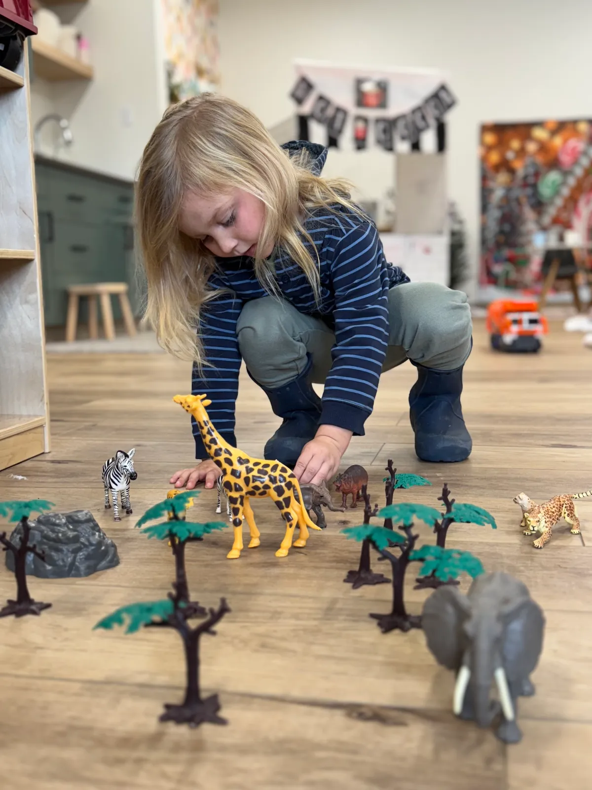 Child arranging safari animals during imaginative play at Spark Academy's Fresh 3's Fridays program